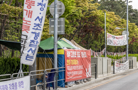 인도 점거한 천막       23일 서울 서초구 양재동 현대자동차 사옥 일대에 현수막이 덕지덕지 걸려 있다. 시민들이 다니는 보행로 한복판에는 불법 시위 천막이 통행을 방해하고 있다.           박동욱기자 fufus@dt.co.kr